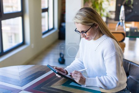 Téléchargez les photos : Jeune adulte jolie femme blonde en utilisant un pad à la maison - en image libre de droit