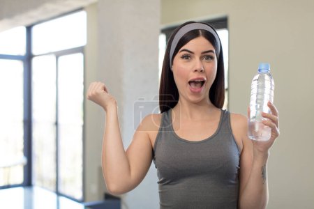 Téléchargez les photos : Jolie jeune femme se sentant choquée, riant et célébrant le succès. concept de bouteille d'eau - en image libre de droit