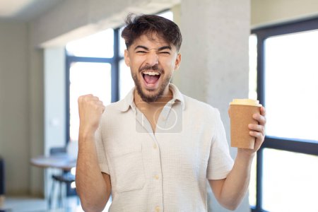 Téléchargez les photos : Jeune homme beau se sentant choqué, riant et célébrant le succès. concept de café à emporter - en image libre de droit