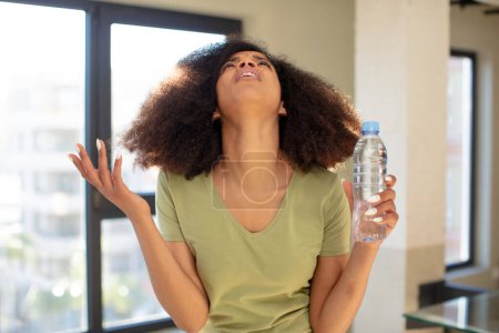 Téléchargez les photos : Jolie afro femme noire criant avec les mains en l'air. concept de bouteille d'eau - en image libre de droit