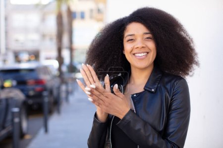 Téléchargez les photos : Afro-américaine jolie femme se sentant heureuse et réussie, souriant et applaudissant les mains, disant félicitations avec un applaudissement - en image libre de droit
