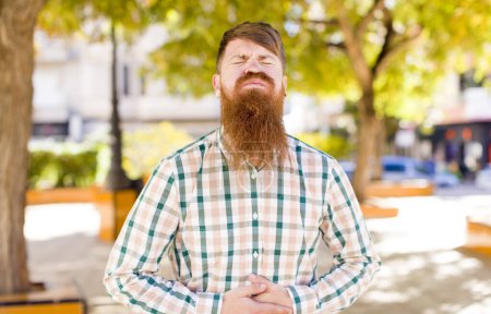 Photo for Red hair bearded man with a goofy, crazy, surprised expression, puffing cheeks, feeling stuffed, fat and full of food - Royalty Free Image