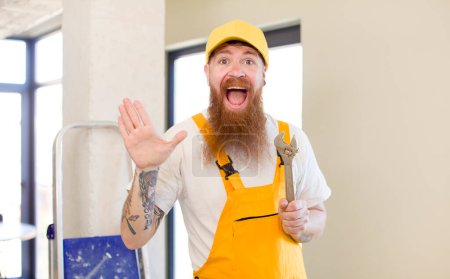 Téléchargez les photos : Homme aux cheveux roux se sentant heureux et étonné de quelque chose d'incroyable réparer la maison. concept bricoleur - en image libre de droit