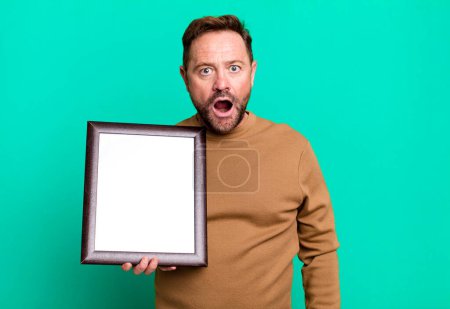 Foto de Hombre de mediana edad que parece muy sorprendido o sorprendido con un marco vacío - Imagen libre de derechos