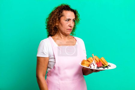 Photo for Pretty middle age woman feeling sad, upset or angry and looking to the side. home made waffles concept - Royalty Free Image