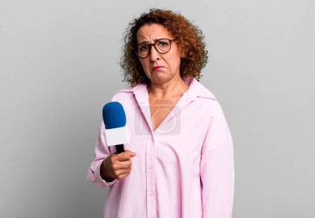 Photo for Pretty middle age woman feeling sad and whiney with an unhappy look and crying. tv presenter with a microphone concept - Royalty Free Image