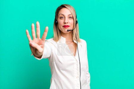 Photo for Pretty blonde woman smiling and looking friendly, showing number four. telemarketer concept - Royalty Free Image