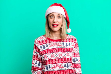 Photo for Pretty blonde woman looking happy and pleasantly surprised. christmas and santa hat concept - Royalty Free Image