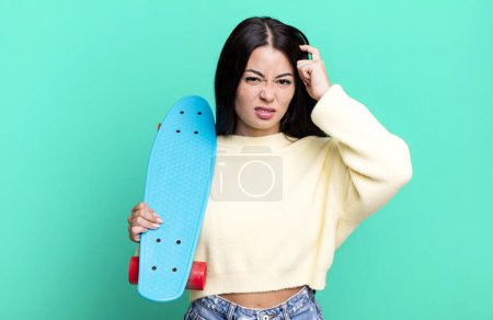 Photo for Hispanic pretty woman feeling confused and puzzled, showing you are insane. skate boarding concept - Royalty Free Image