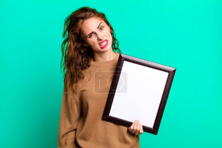 Téléchargez les photos : Hispanic pretty woman feeling puzzled and confused with an empty blank frame - en image libre de droit