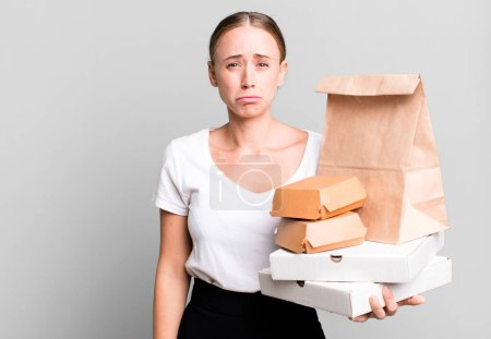 Photo for Caucasian pretty woman feeling sad and whiney with an unhappy look and crying. with fast food packages. delivery concept - Royalty Free Image