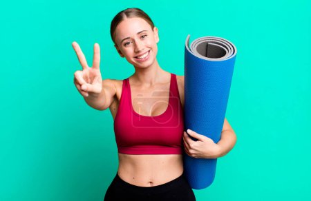 Photo for Caucasian pretty woman smiling and looking happy, gesturing victory or peace. fitness and yoga concept - Royalty Free Image