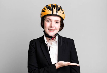 Foto de Joven bonita mujer sonriendo alegremente, sintiéndose feliz y mostrando un concepto. concepto de bicicleta y mujer de negocios - Imagen libre de derechos