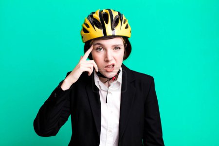 Photo for Young pretty woman feeling confused and puzzled, showing you are insane. bike and businesswoman concept - Royalty Free Image