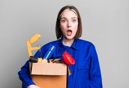 Photo for Young pretty woman looking very shocked or surprised. housekeeper and toolbox concept - Royalty Free Image