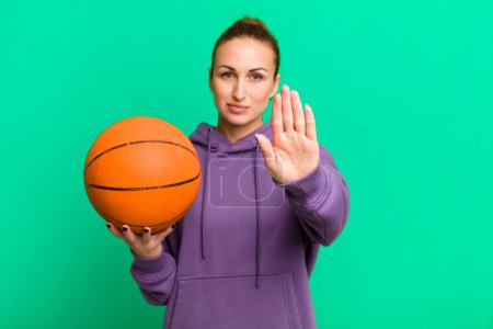 Téléchargez les photos : Jeune jolie femme regardant sérieusement montrant la paume ouverte faisant geste d'arrêt. concept de basket - en image libre de droit
