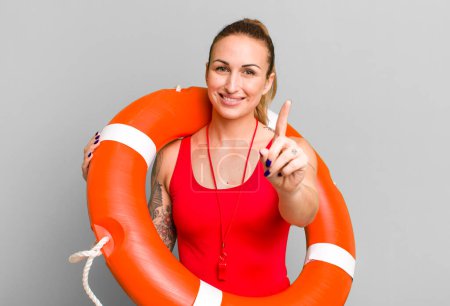 Photo for Young pretty woman smiling proudly and confidently making number one. summer and lifeguard concept - Royalty Free Image