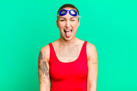 Foto de Joven mujer bonita con actitud alegre y rebelde, bromeando y sacando la lengua. concepto de nadador - Imagen libre de derechos