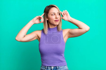 Foto de Blonde adult woman feeling confused or doubting, concentrating on an idea, thinking hard, looking to copy space on side - Imagen libre de derechos