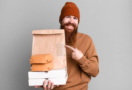 Photo for Young adult red hair bearded cool man with a paper bag with take away food - Royalty Free Image