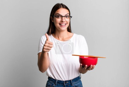 Foto de Young pretty woman feeling proud,smiling positively with thumbs up. japanese ramen noodles concept - Imagen libre de derechos