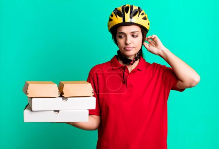 Foto de Young pretty woman smiling happily and daydreaming or doubting. pizza delivery concept - Imagen libre de derechos
