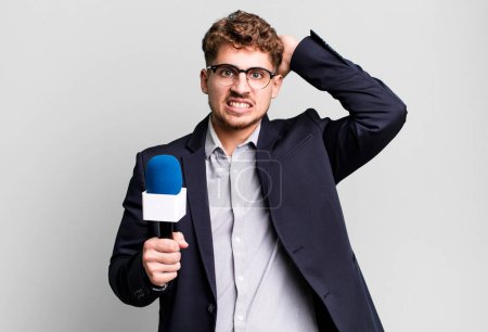 Photo for Young adult caucasian man feeling stressed, anxious or scared, with hands on head. journalist or presenter with a microphone - Royalty Free Image