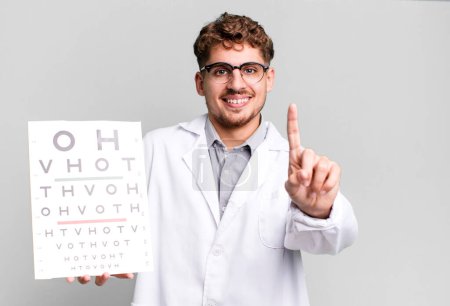 Téléchargez les photos : Jeune homme caucasien adulte souriant et regardant amical, montrant numéro un. concept de test de vision optique - en image libre de droit