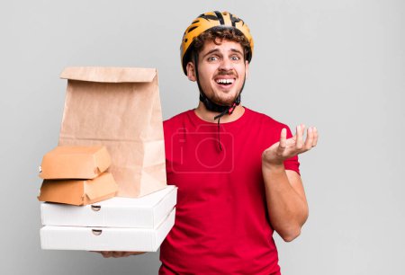 Foto de Joven hombre caucásico adulto buscando desesperado, frustrado y estresado. llevar concepto de entrega de comida rápida - Imagen libre de derechos