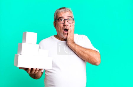 Foto de Hombre mayor de mediana edad sintiéndose sorprendido y asustado. cajas en blanco de diferentes paquetes - Imagen libre de derechos