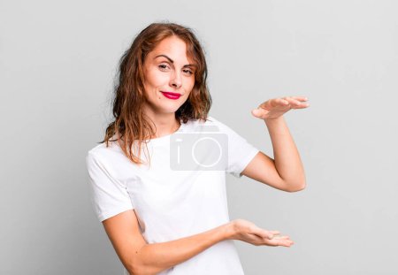 Téléchargez les photos : Jeune jolie femme tenant un objet avec les deux mains sur le côté copier l'espace, montrant, offrant ou annonçant un objet - en image libre de droit