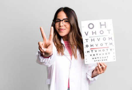 Photo for Hispanic pretty woman smiling and looking happy, gesturing victory or peace. optometry concept - Royalty Free Image