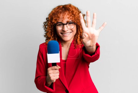 Téléchargez les photos : Cheveux roux jolie femme souriante et sympathique, montrant le numéro quatre. concept de journaliste et présentateur - en image libre de droit