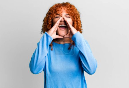 Photo for Redhair pretty woman feeling happy, excited and positive, giving a big shout out with hands next to mouth, calling out - Royalty Free Image