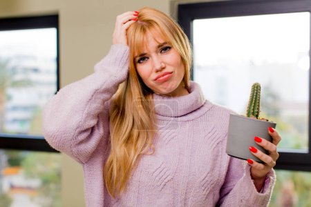 Téléchargez les photos : Jeune jolie femme tenant un cactus à l'intérieur de la maison - en image libre de droit