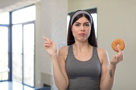 Photo for Pretty young woman crossing fingers and hoping for good luck. donut concept - Royalty Free Image