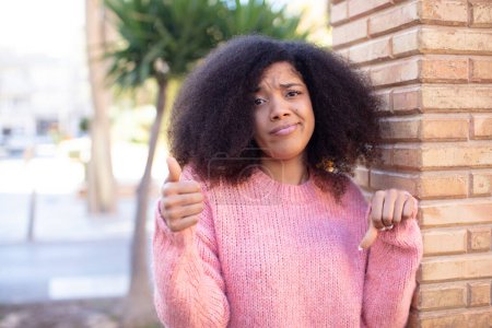 Téléchargez les photos : Afro-américaine jolie femme se sentant confus, ignorant et incertain, pesant le bien et le mal dans différentes options ou choix - en image libre de droit