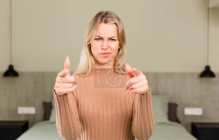 Photo for Young pretty woman pointing forward at camera with both fingers and angry expression, telling you to do your duty. bed concept - Royalty Free Image