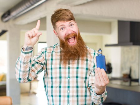 Photo for Red hair man feeling like a happy and excited genius after realizing an idea with a vaper - Royalty Free Image