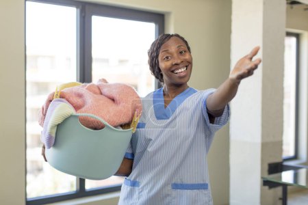 Foto de Negro afro mujer sonriendo felizmente y ofreciendo o mostrando un concepto. concepto de lavandería y limpieza - Imagen libre de derechos