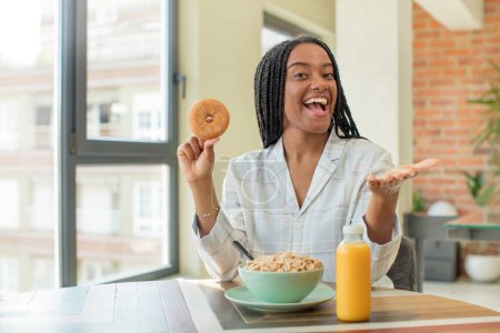 Foto de Negro afro mujer sonriendo felizmente y ofreciendo o mostrando un concepto. concepto de desayuno - Imagen libre de derechos