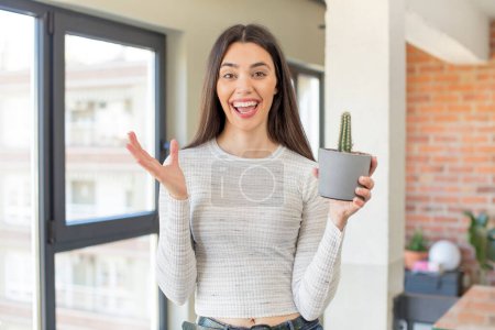 Photo for Pretty young model feeling happy and astonished at something unbelievable. decorative cactus concept - Royalty Free Image
