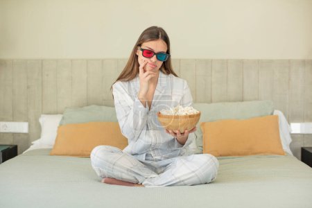Téléchargez les photos : Jeune jolie femme se sentant ennuyée, frustrée et endormie après une fatigue. popcorns et concept de film - en image libre de droit