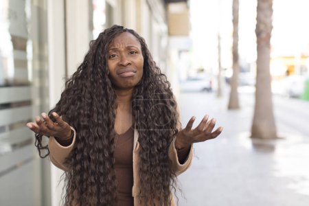 Téléchargez les photos : Afro jolie femme noire regardant perplexe, confus et stressé, se demandant entre différentes options, se sentant incertain - en image libre de droit
