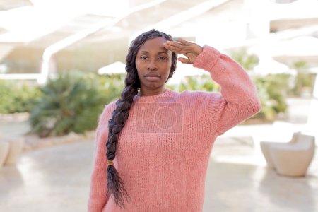 Téléchargez les photos : Afro jolie femme noire saluant la caméra avec un salut militaire dans un acte d'honneur et de patriotisme, faisant preuve de respect - en image libre de droit