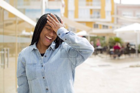 Photo for Afro pretty black woman laughing and slapping forehead like saying doh! I forgot or that was a stupid mistake - Royalty Free Image