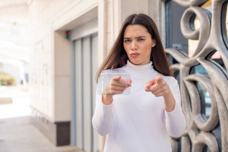 Photo for Pretty young adult woman pointing forward at camera with both fingers and angry expression, telling you to do your duty - Royalty Free Image