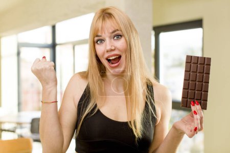 Photo for Young pretty woman with a chocolate bar at home interior - Royalty Free Image