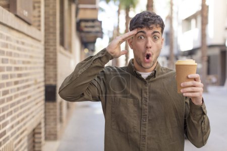 Téléchargez les photos : Jeune homme beau regard heureux, étonné et surpris. concept de café à emporter - en image libre de droit
