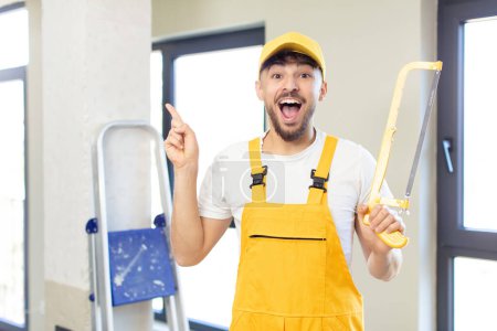 Photo for Young handsome man feeling like a happy and excited genius after realizing an idea. handyman with a saw - Royalty Free Image